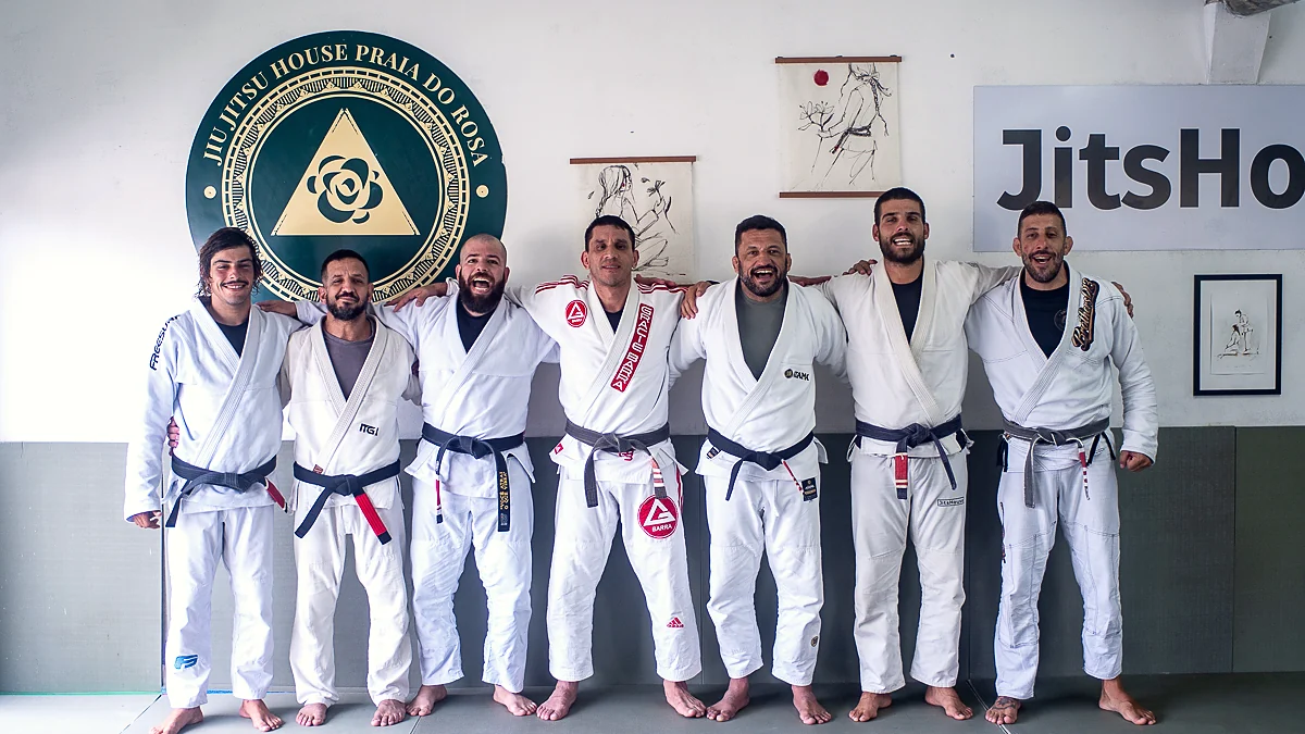 Turma enfileirada de kimono diante do selo da Jiu-Jitsu House Praia do Rosa.