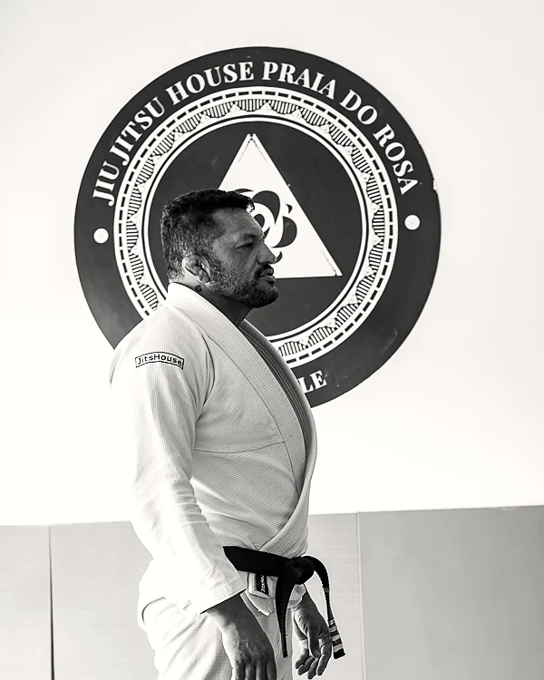 Rodrigo Klippel de perfil, de kimono, diante do selo da casa.