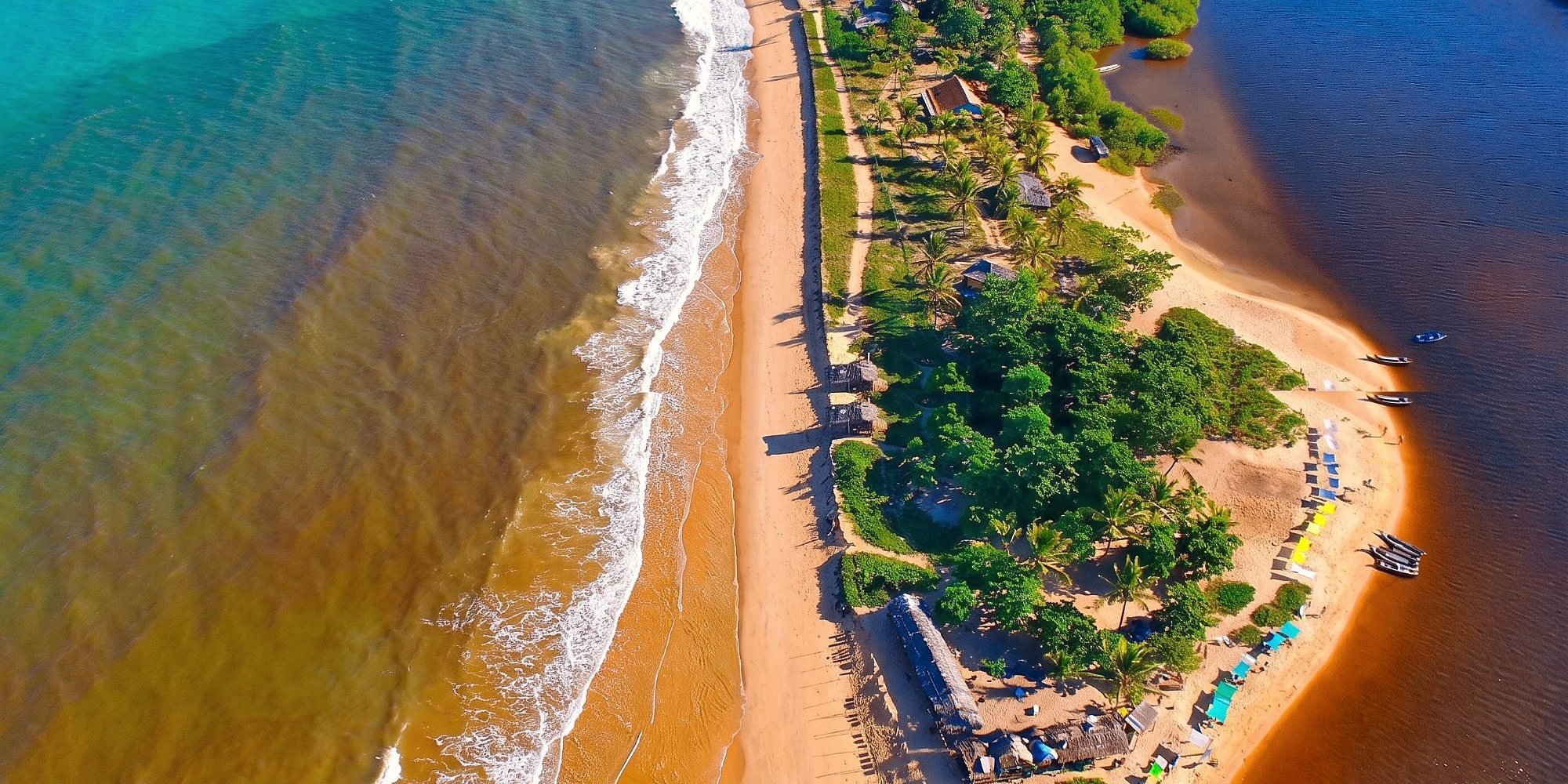 Caraíva vista de cima: o mar de um lado, o rio do outro e a faixa de areia com a vila no meio.