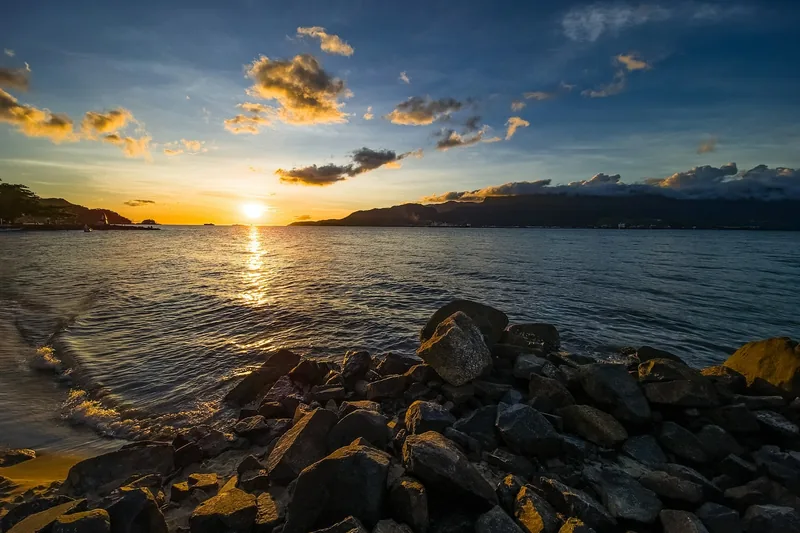 Pôr do sol sobre o mar, visto das pedras da praia.