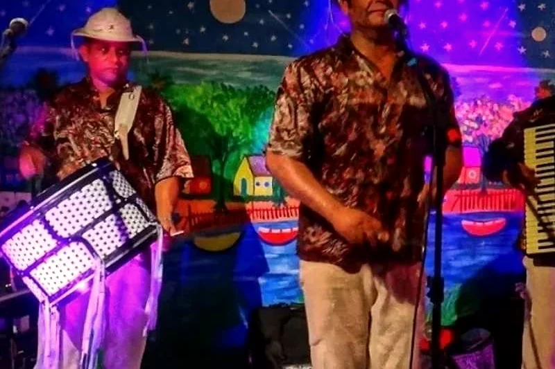 Banda de forró tocando à noite, sob luzes coloridas.