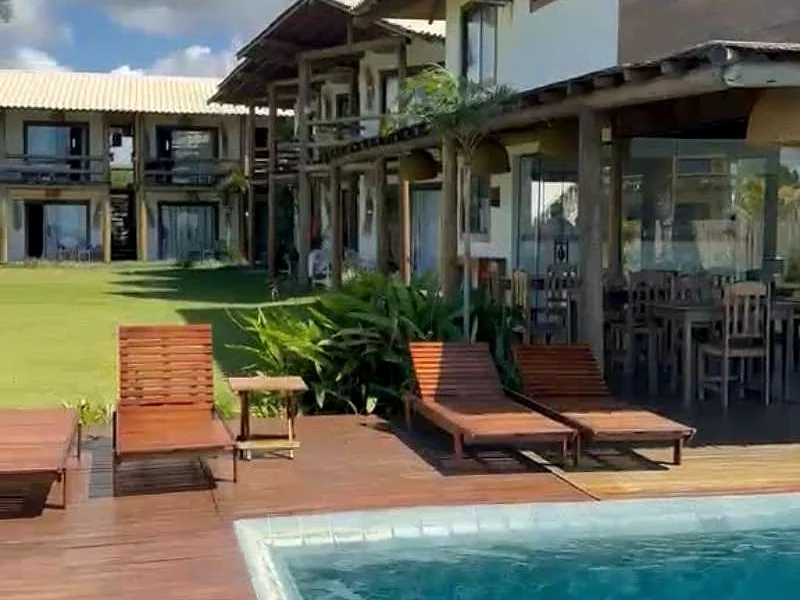 Piscina da pousada com espreguiçadeiras e jardim.