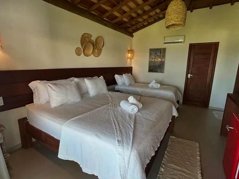 Quarto da pousada com cama de casal arrumada.