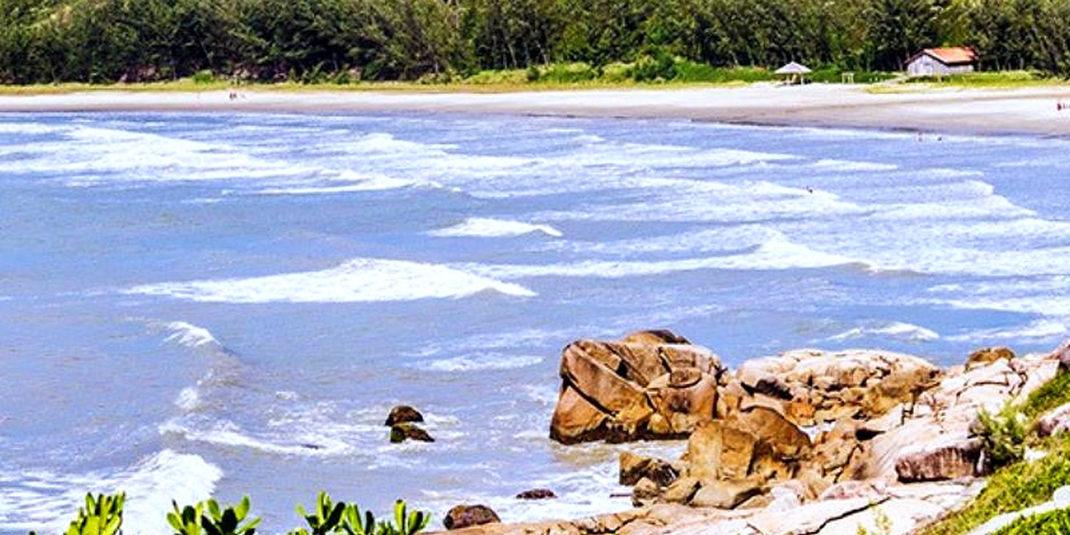 Vista do alto da enseada da Praia do Rosa, mar turquesa e morros verdes.