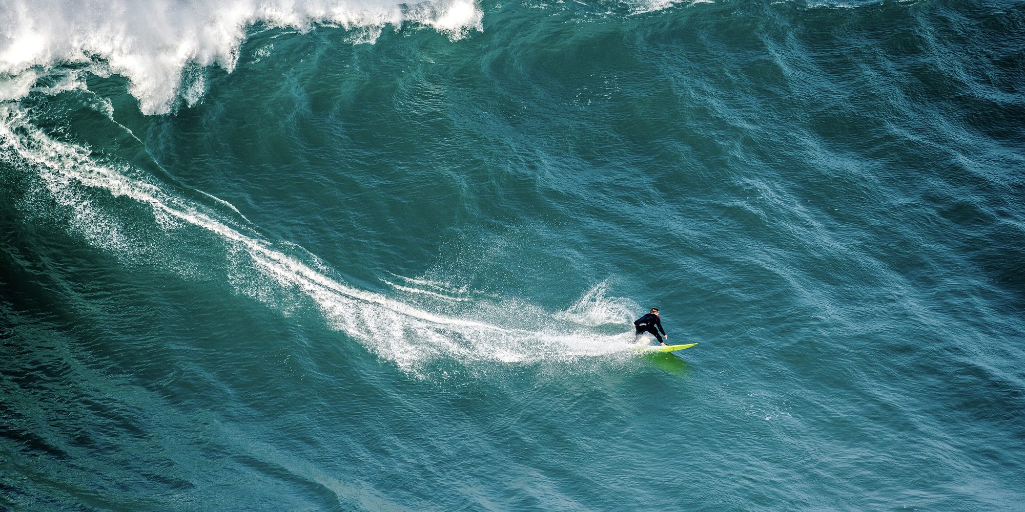 Surfista descendo uma onda gigante na Praia do Norte, em Nazaré.