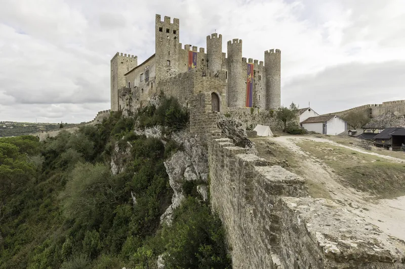 Torres e muralhas do Castelo de Óbidos sobre a encosta.