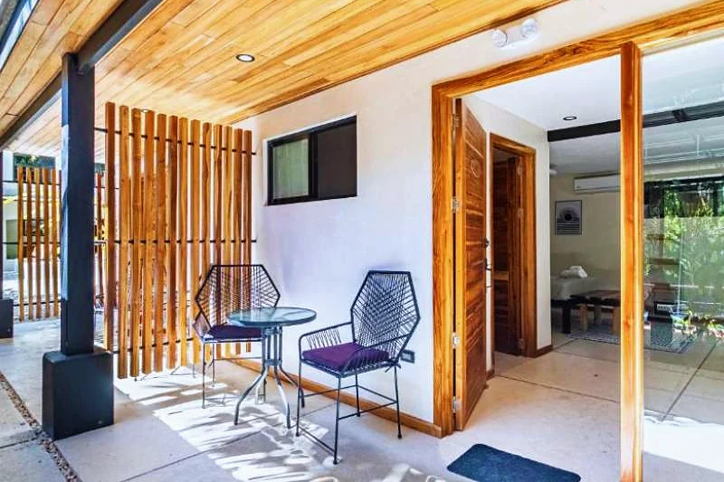 Sala de estar do hotel, com pé-direito de madeira e portas abertas para a mata.