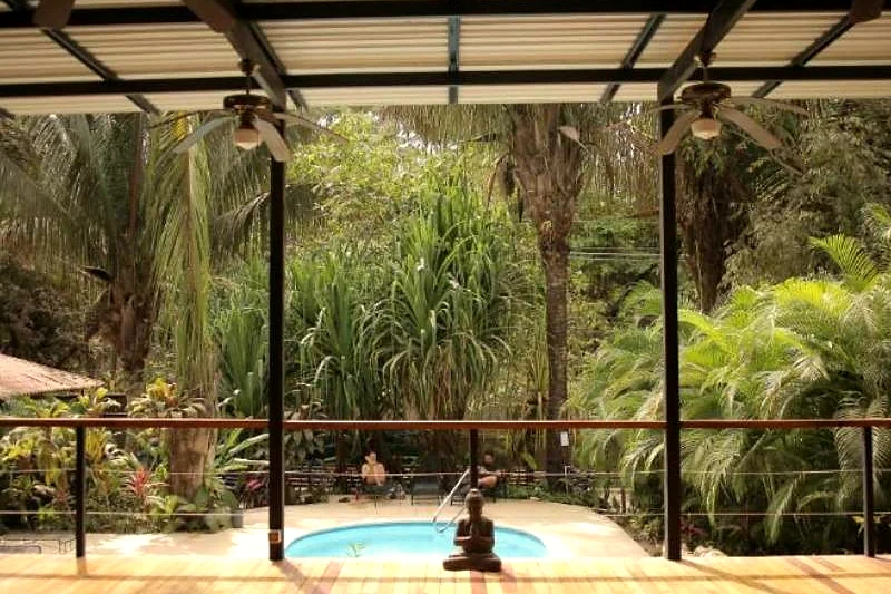 Shala de yoga de madeira aberta para a mata, com vista para a piscina do hotel.
